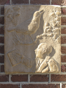 905515 Afbeelding van een stenen reliëf met een zangvogel en een lezende man, aan de gevel van het pand Schoolstraat 26 ...